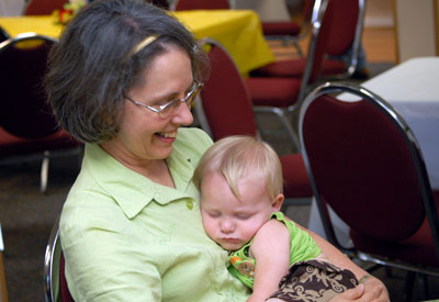 A little boy relaxing on a woman's lap in the fellowship hall